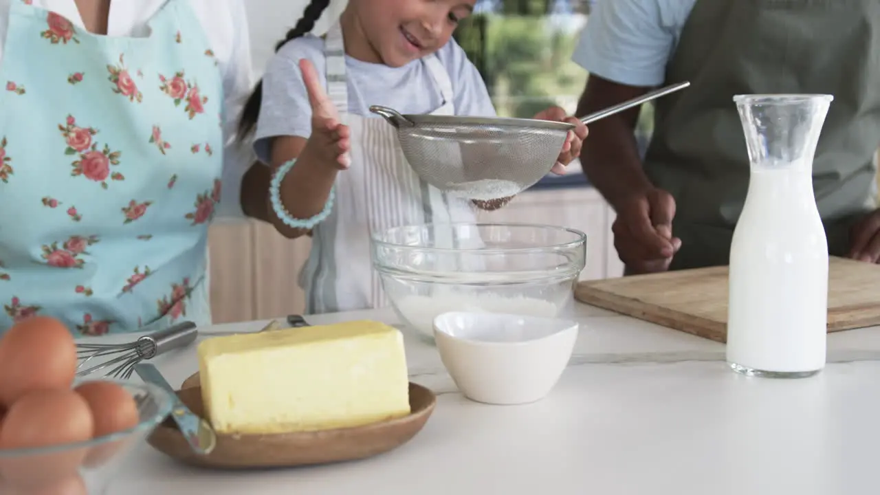 Biracial girl with dark hair helps in the kitchen giving a thumbs-up