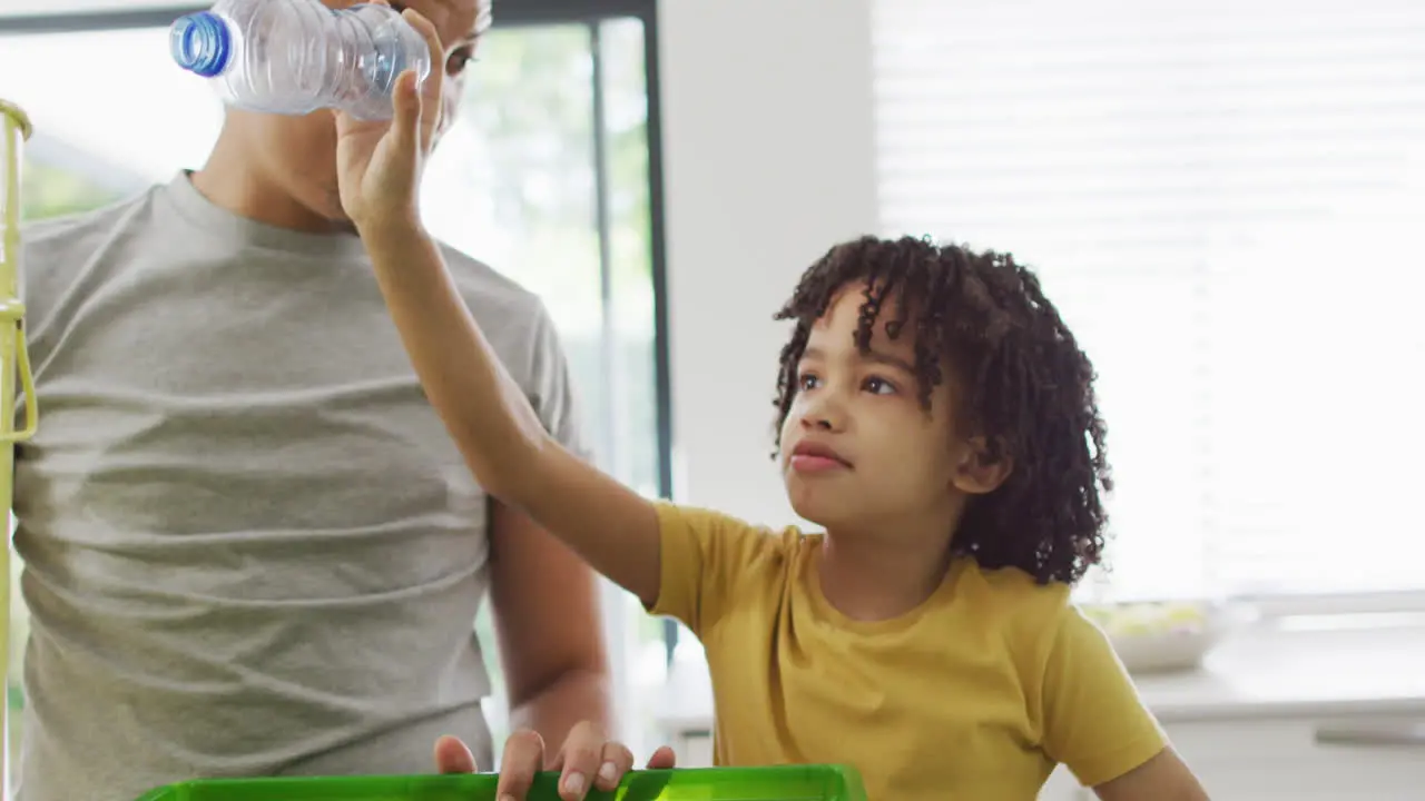 A young boy gives his father a high-five in the kitchen with copy space