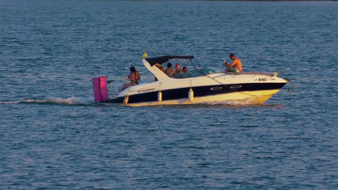 Group of friends having fun on a boat trip on lake golden hour in slow motion