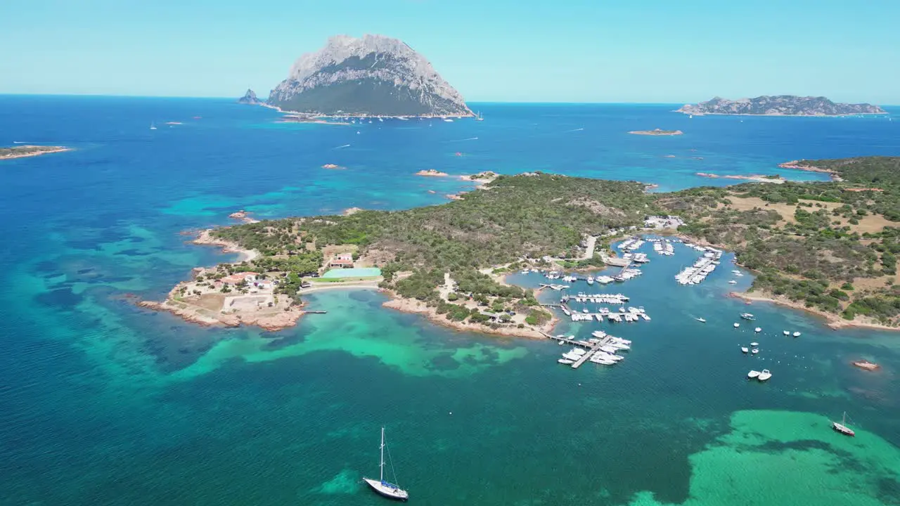 Porto San Paolo and Tavolara Island surrounded by boats and turquoise blue sea in Sardinia Italy Aerial 4k