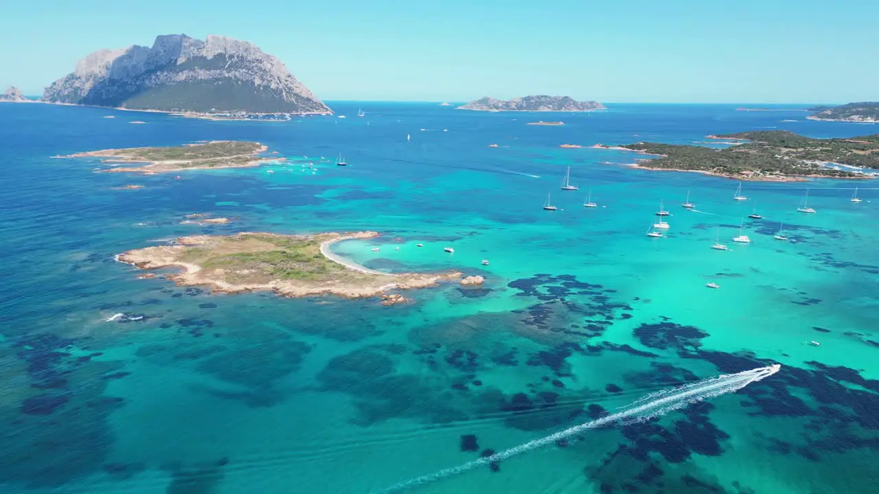 Tavolara and Cavalli Island surrounded by boats and turquoise blue sea in Sardinia Italy Aerial 4k