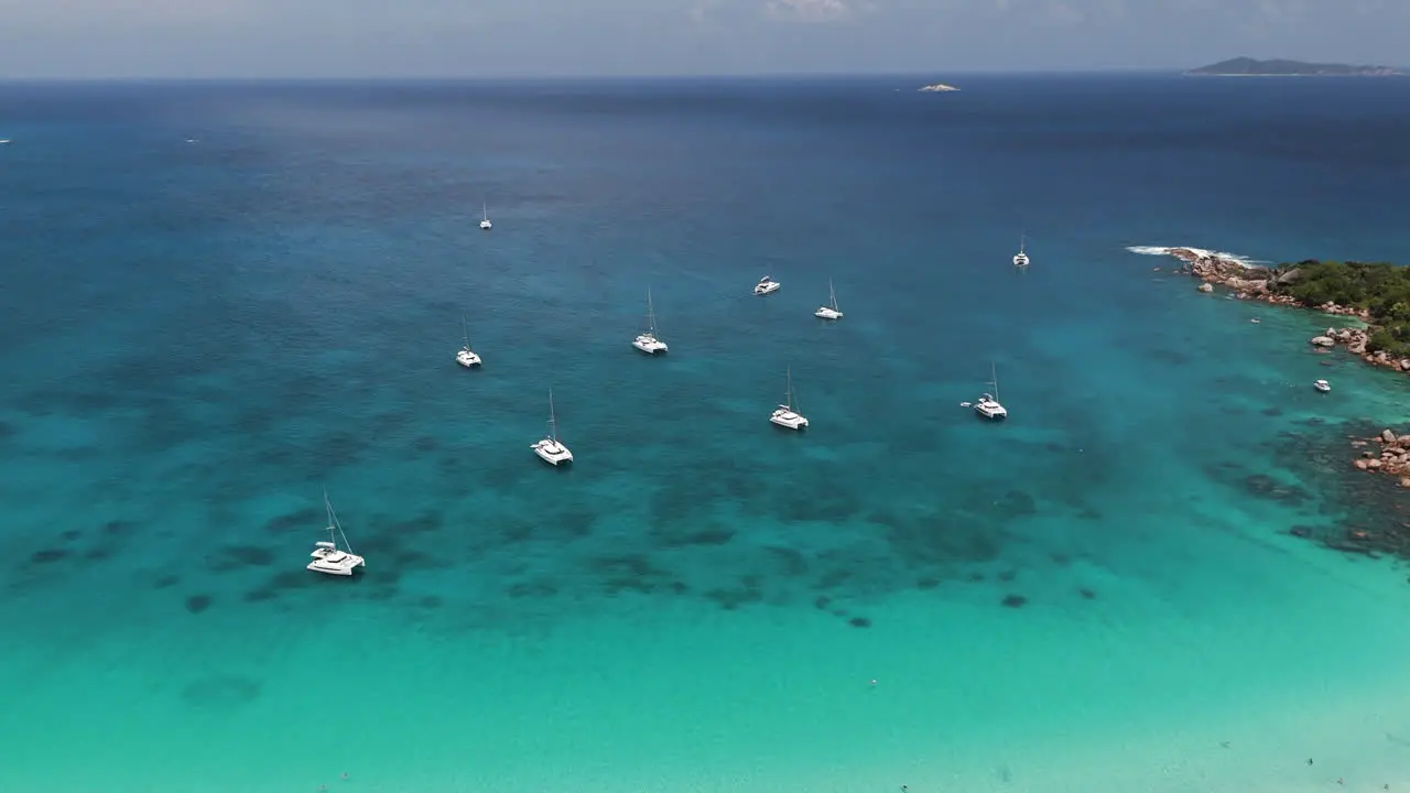 Drone shot of a couple boats under anchor at a beautiful tropical beach in crystal clear water at the Seychelles