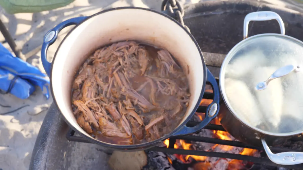 Some beef and corn being cooked on the campfire