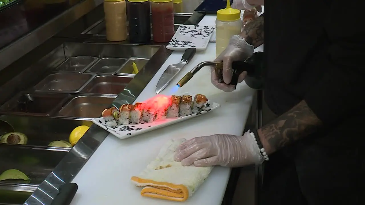 CHEF SEARING SUSHI ROLL AT RESTAURANT