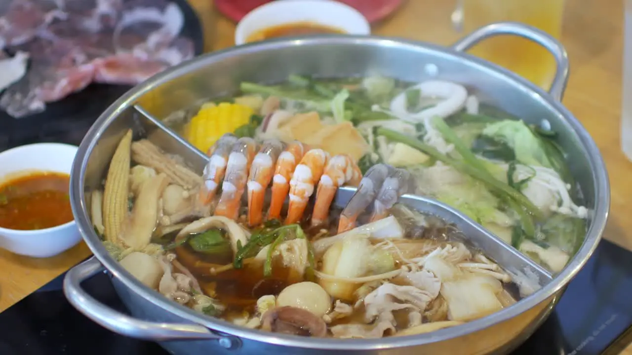 4k video POV while putting pork slice meat into hotpot shabu shabu full with vegetable and meat