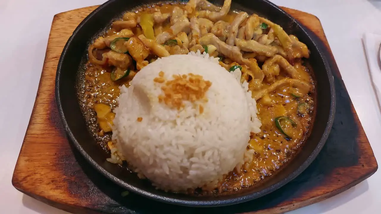 Overhead view of sizzling bicol express and rice on a hot plate a popular authentic traditional dish from the Philippines