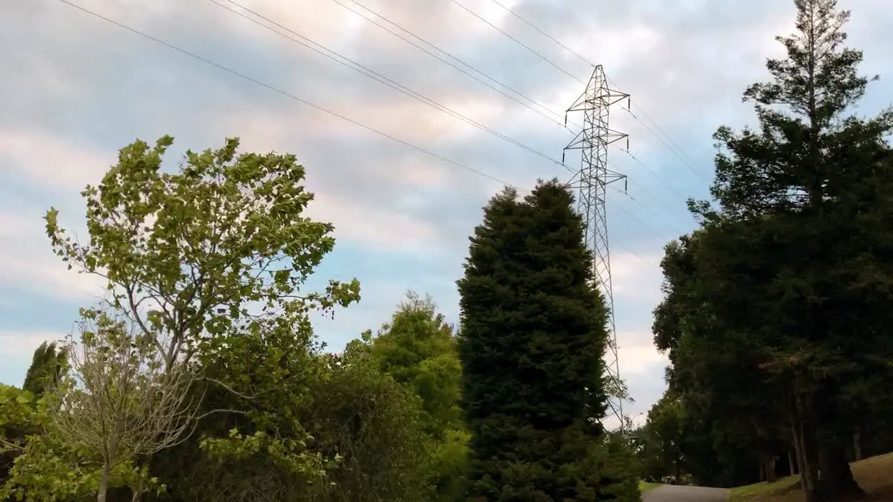 Time lapse of a high voltage power pylon tower rising high above the trees on a sunny day