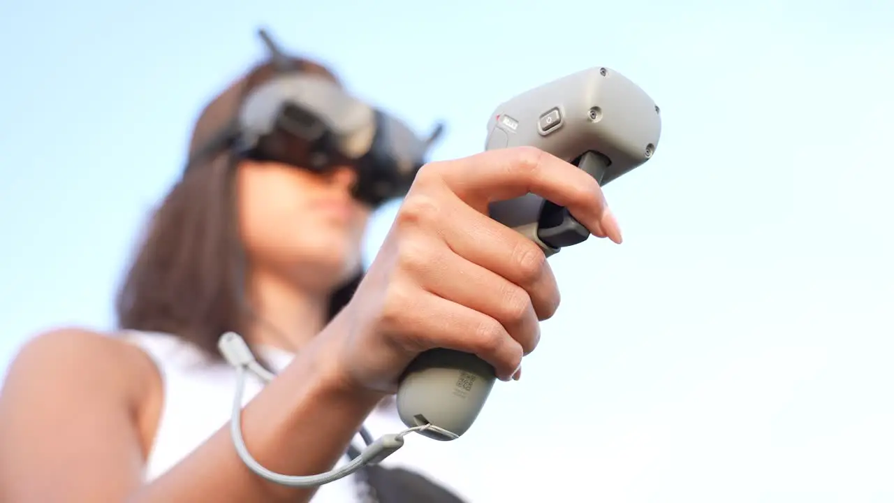 Close Up of Young Woman Hand Holding Remote Motion Controller With Goggles Headset on Her Head Selective Focus Low Angle