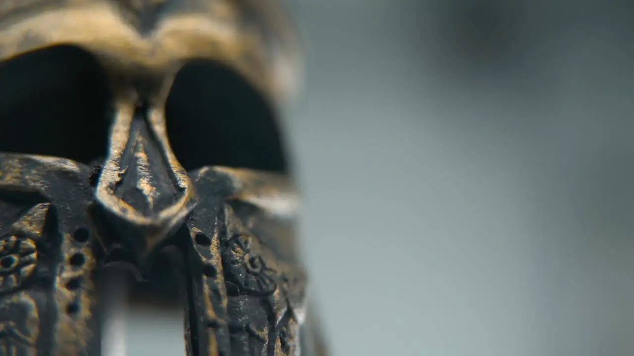 A close-up macro shot of a Spartan design two different ancient warrior metal bronze helmets textured shapes studio lighting Full HD cinematic video hyper Slow Motion 120 fps pan left