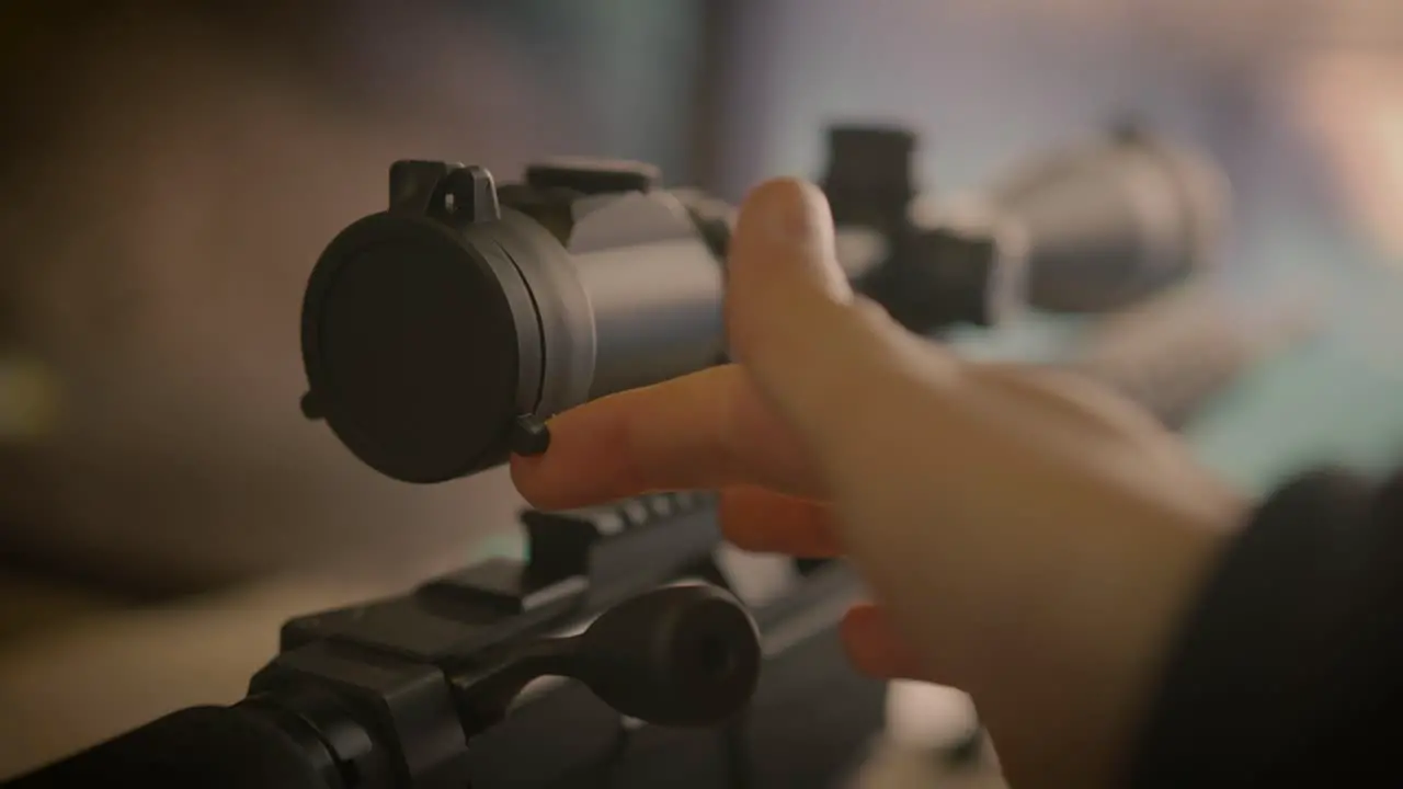 Close up on finger opening scope cover of sniper precision rifle