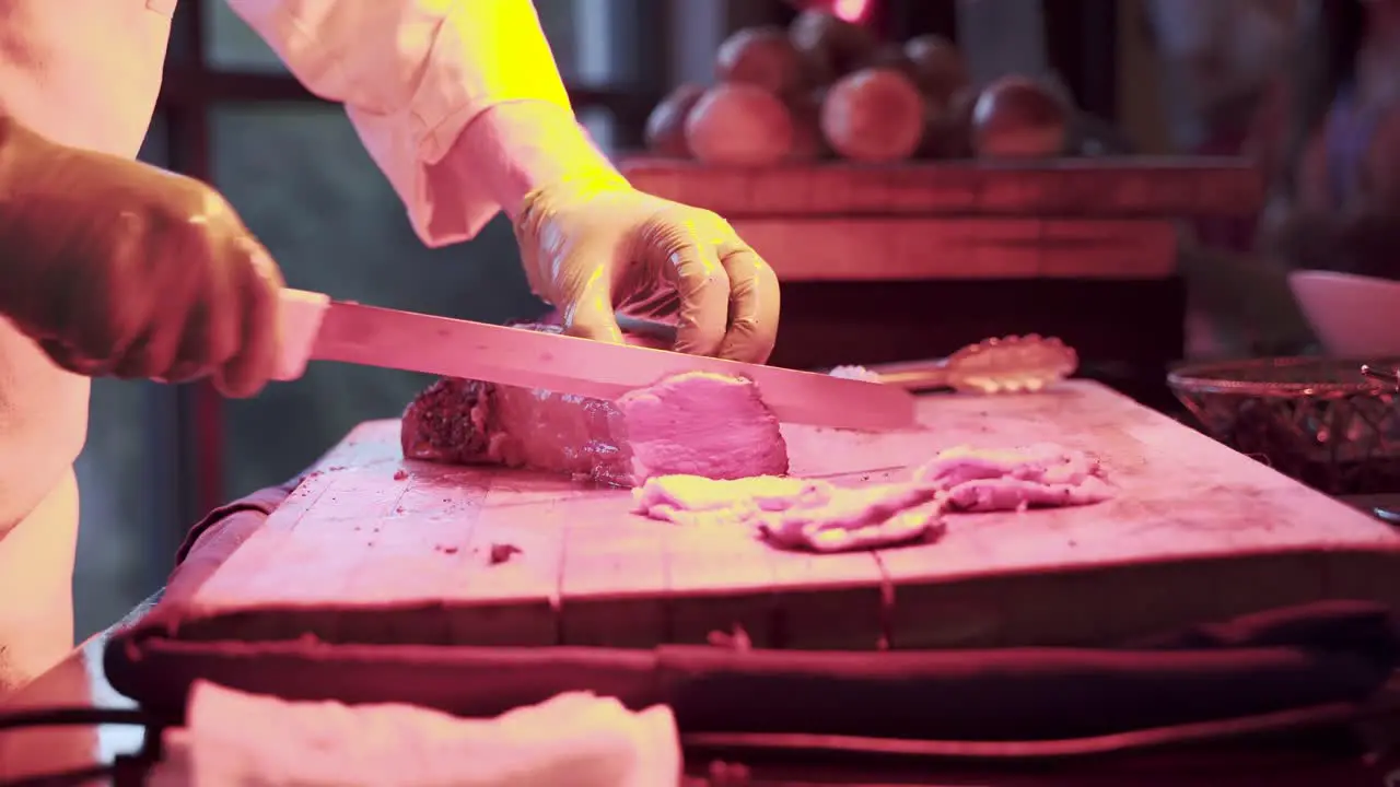 Chef Cutting A Slice Of Cooked Red Meat With A Knife At Buffet