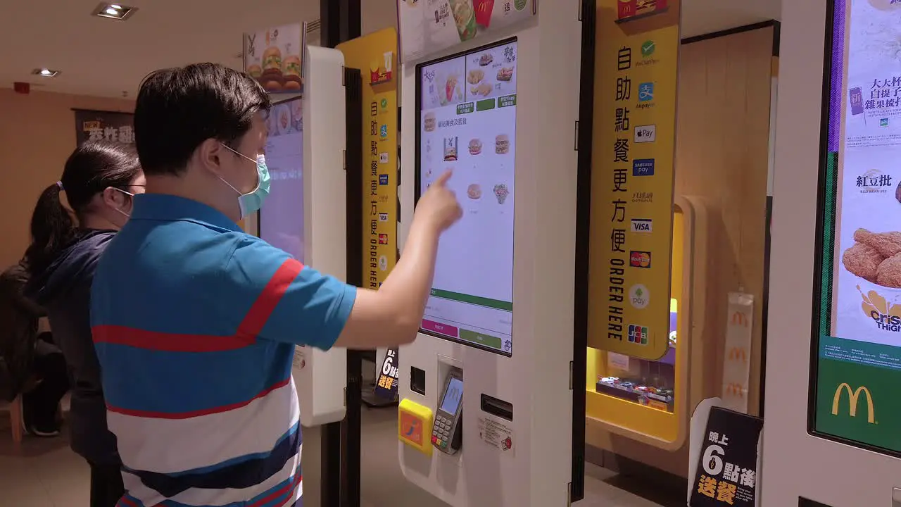 Corona Virus Pandemic Locals using Mcdonalds self service order screens wearing protective face masks in downtown Hong Kong