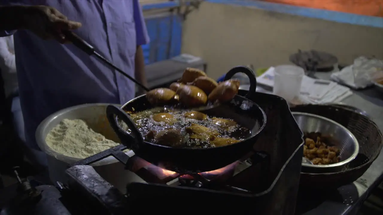 The fried street food is lifted out of the cast iron pot of oil for draining and drying