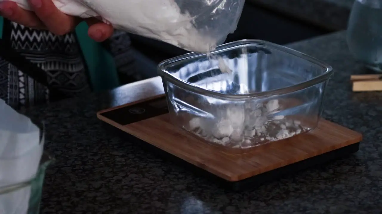 Weighing flour for brownies in a glass bowl and bamboo scale