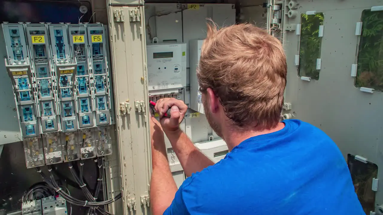 Male electrician connects wires from solar panel into electric power grid