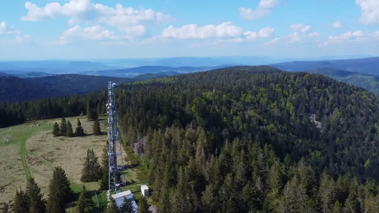 Aerial fly along a tall telecommunication antenna mast pylon among mountain forest in Sérichamp Vosges France 4K