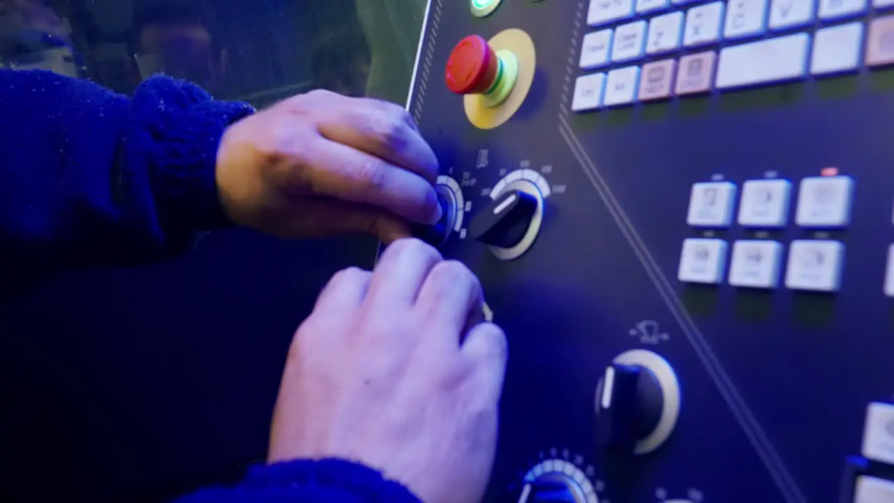 Moving slow motion shot of a Caucasian man's hands moving knobs on a technology board full of buttons and knobs