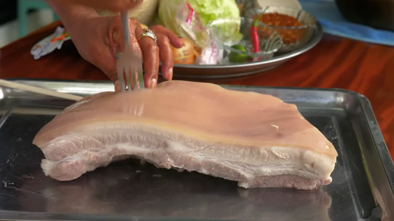 Rubbing salt and stabbing pork belly with fork in handheld view