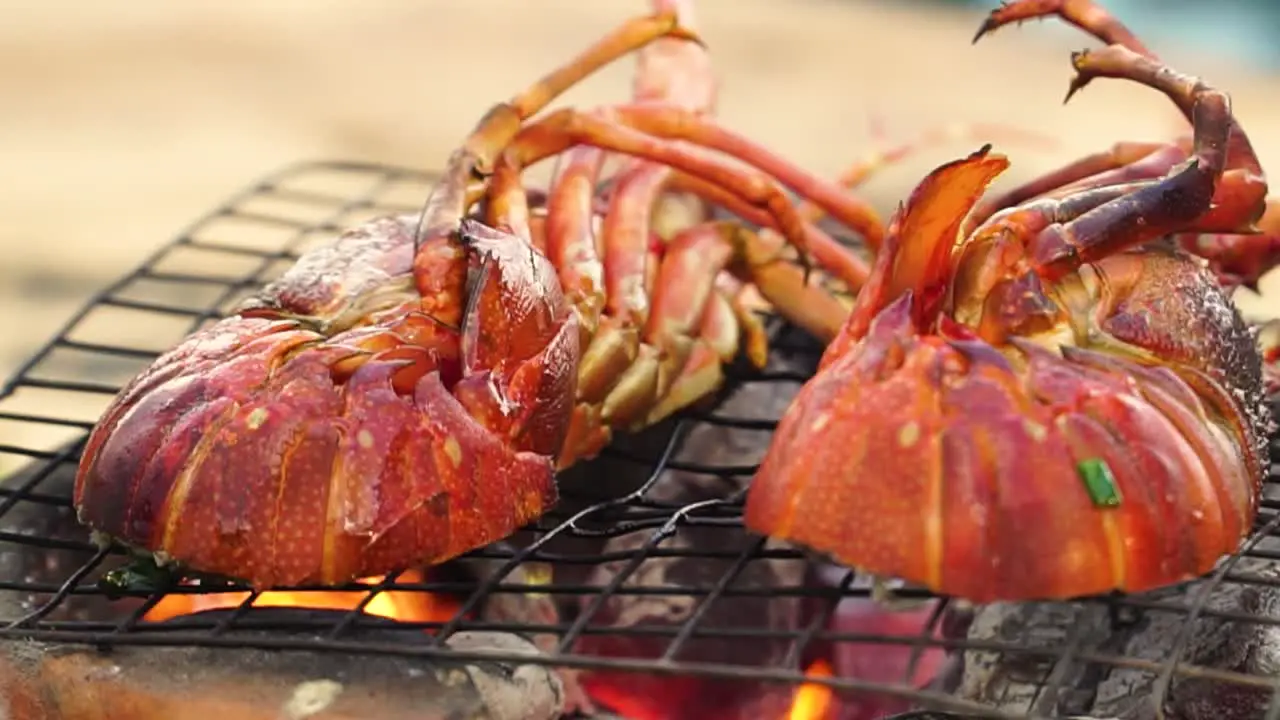 Lobster halves on grate are grilled on open fire small charcoal stove close up