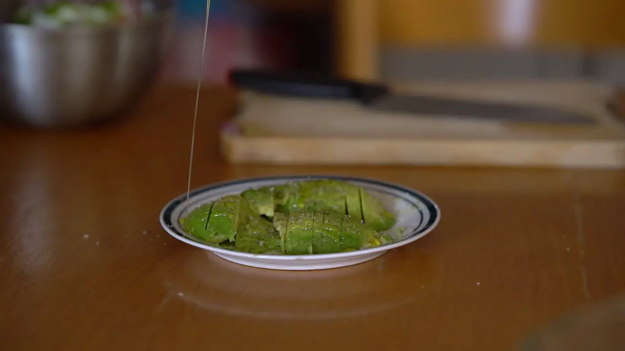 adding olive oil to fresh sliced avocado