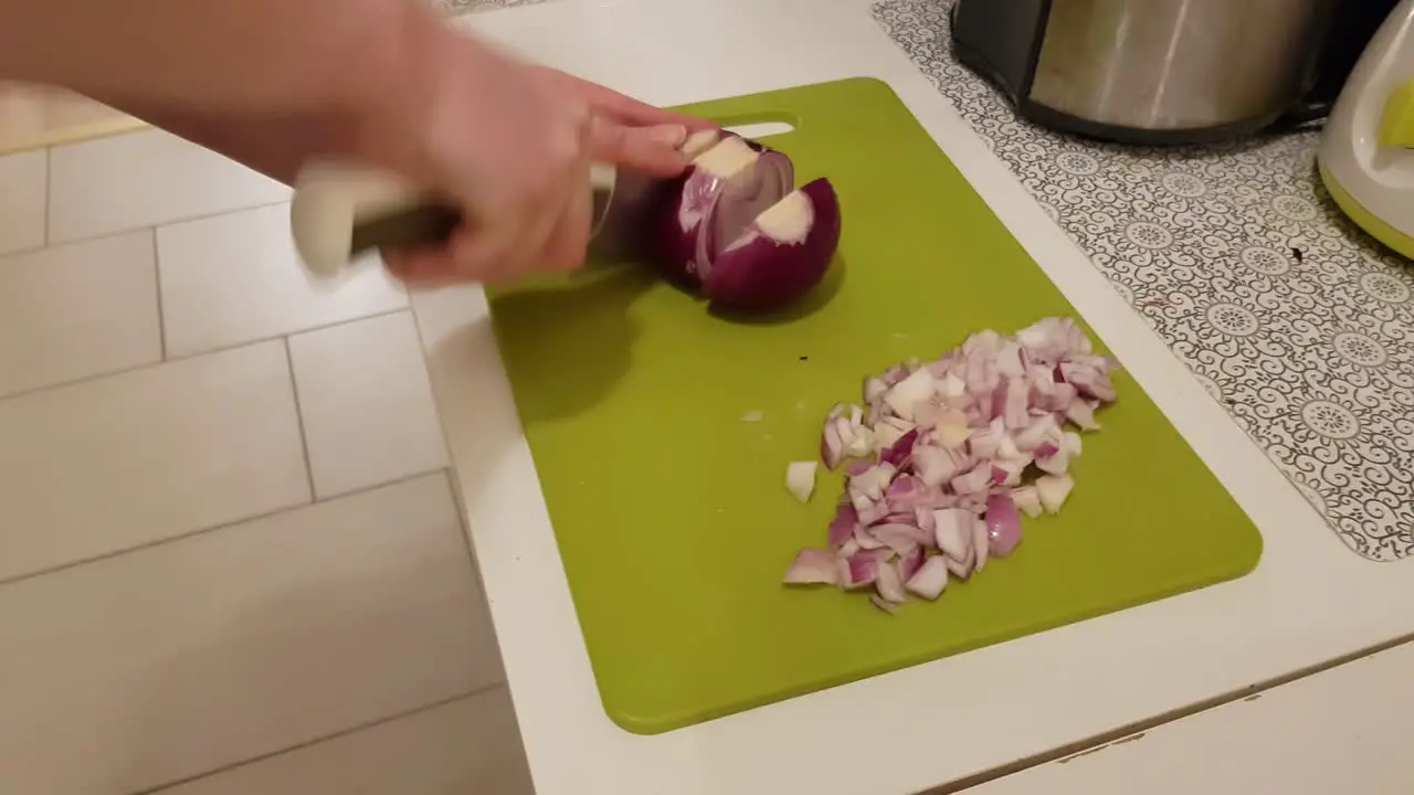 Caucasian woman cooking and cutting up purple onion