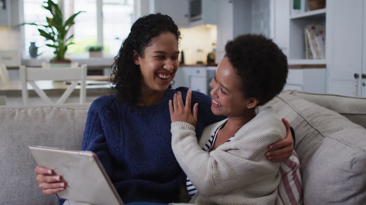 Mixed race lesbian couple sitting on couch and 