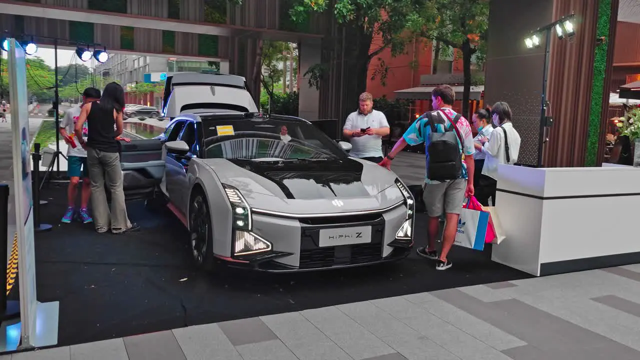 New Chinese EV car model exhibited in a luxury residential area with people having a look