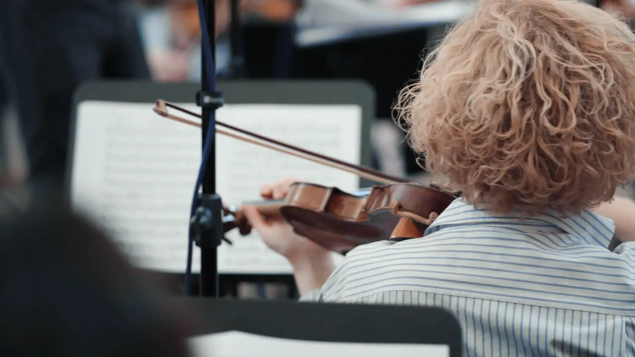 A violinist in the back plays classical music in an orchestra