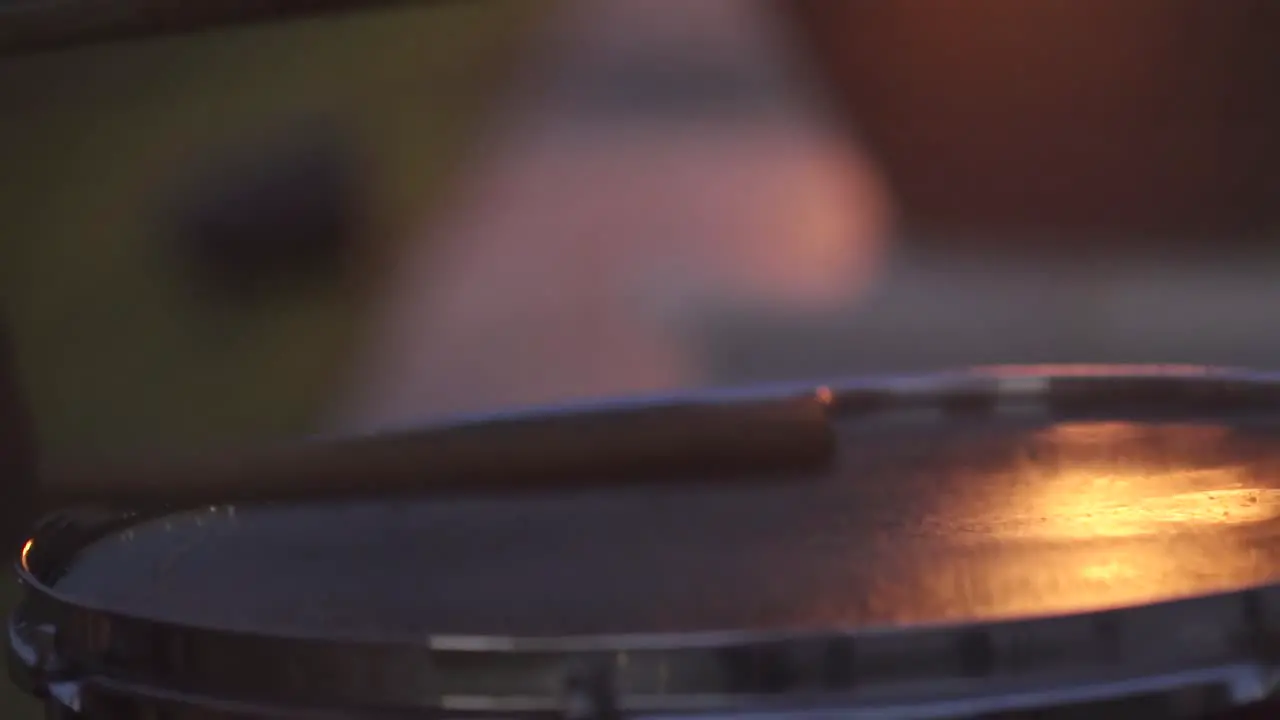 Slow Motion of drum sticks hitting top of drum at night with reflection of fire on top of drum