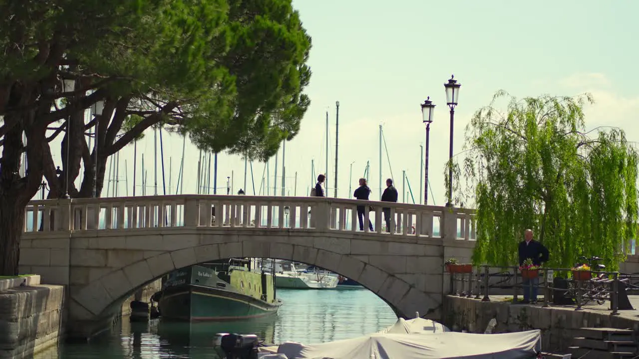 Woman crossing an old stone bridge near a small port of a lake