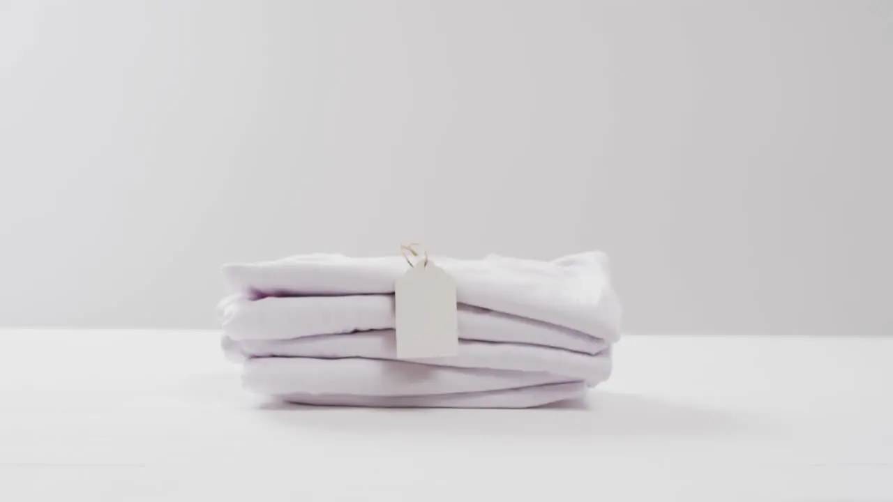 Video of stack of folded white t shirts with copy space on white background