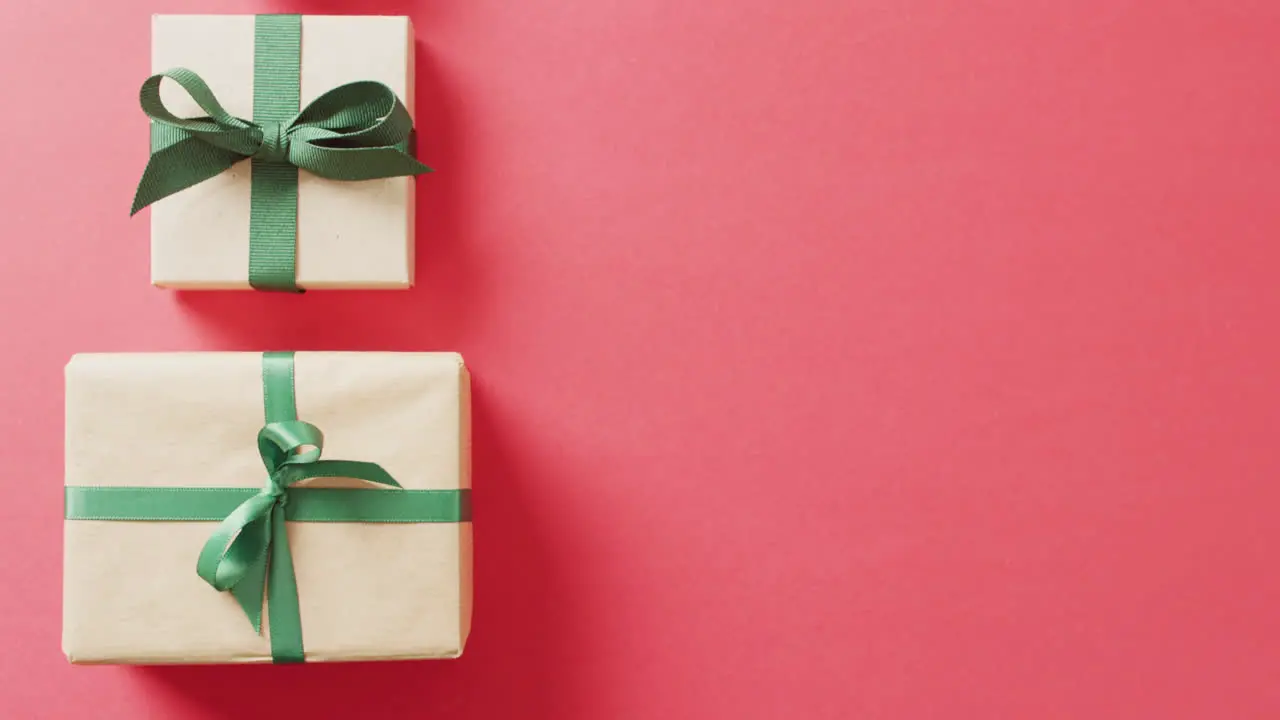 Video of christmas gifts and ribbon forming christmas tree and copy space on pink background