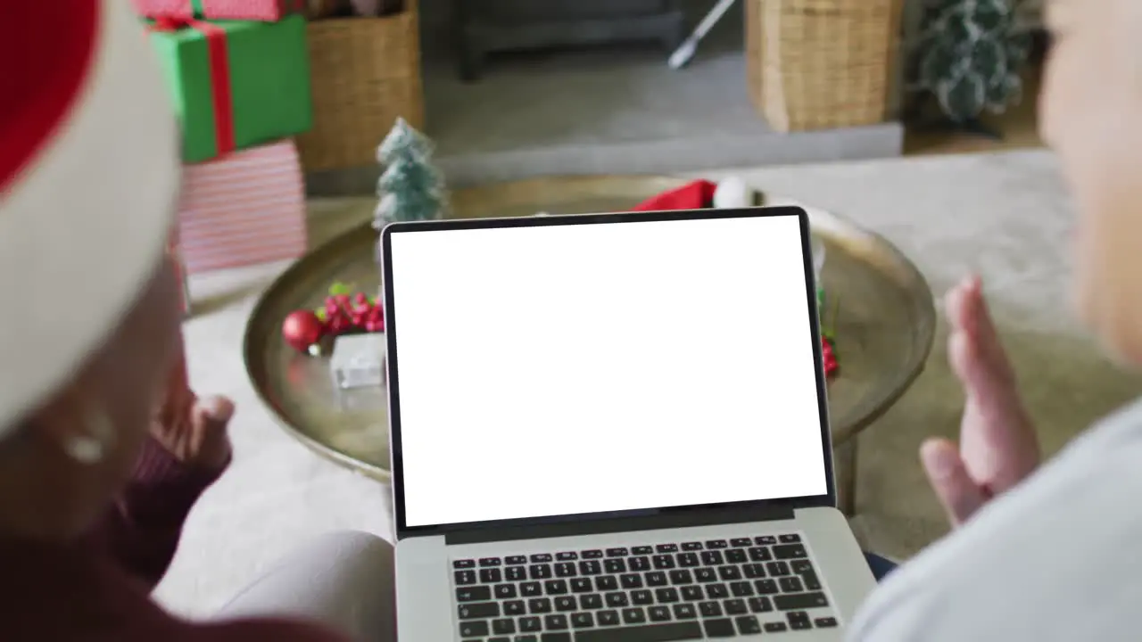 Waving diverse senior female friends making laptop christmas video call copy space on screen