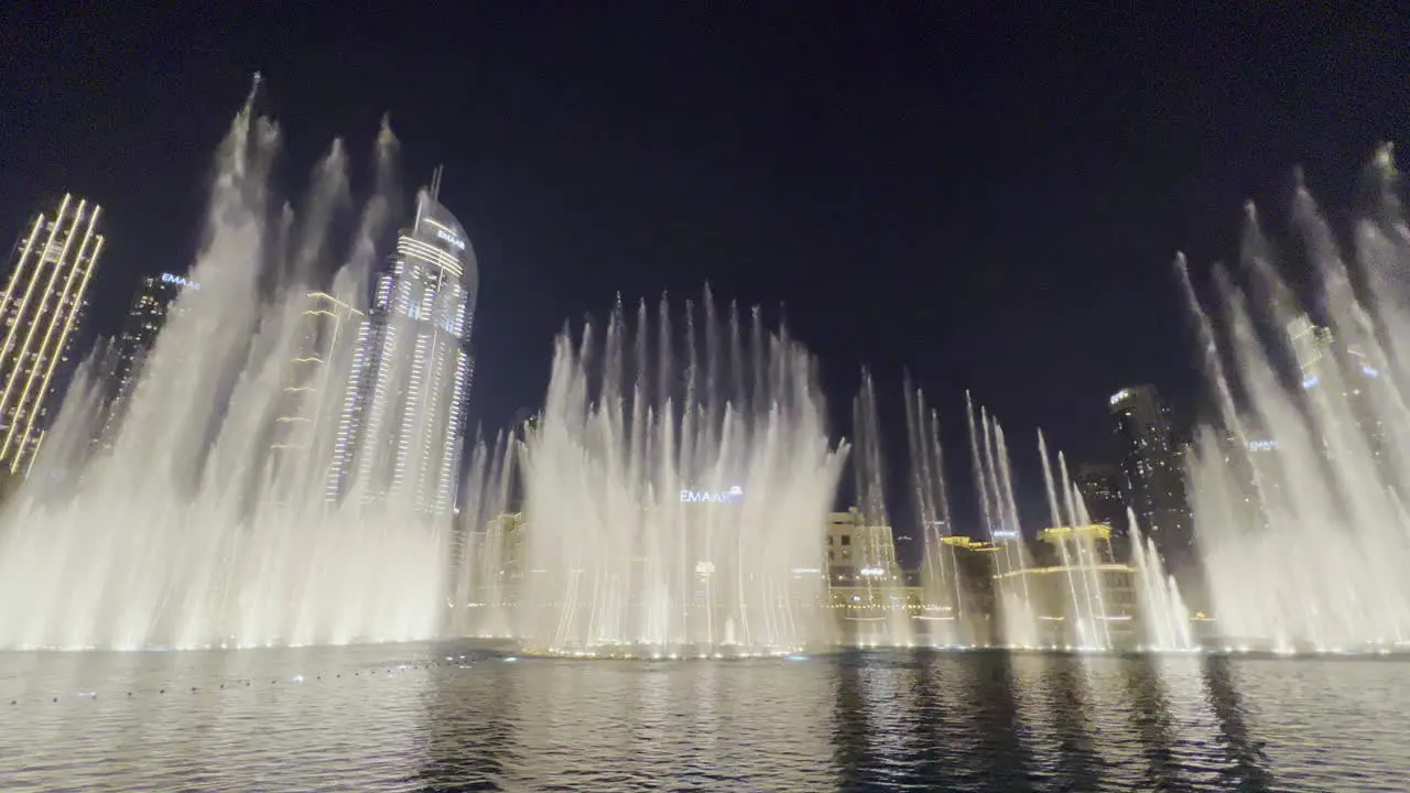 The water show from Dubai fountain seen at night with the cityscape as a background