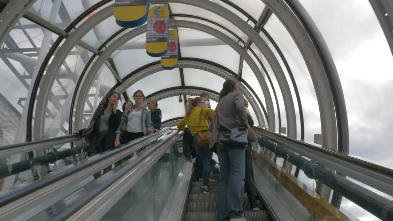 People riding escalators in glass tube