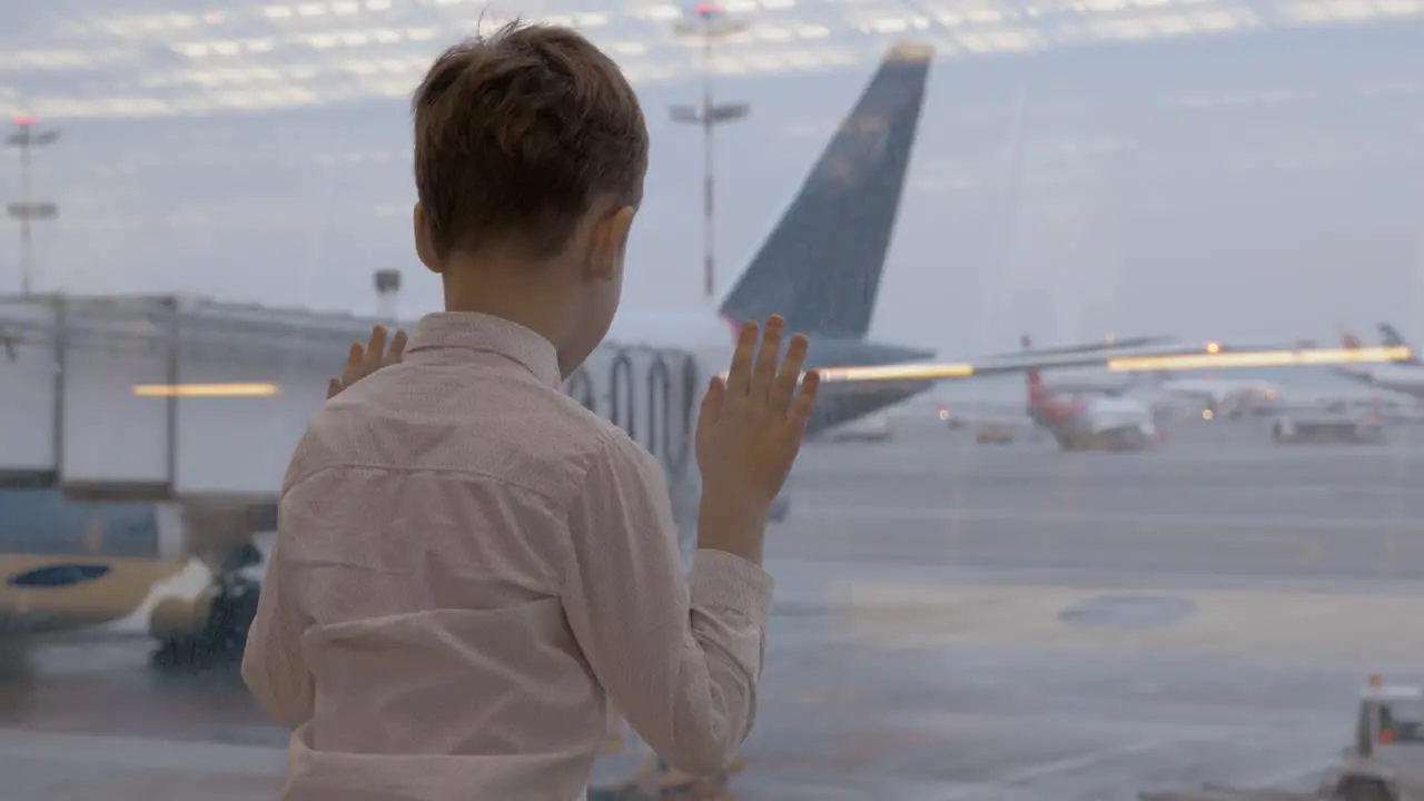 Child waiting for flight and looking at planes through the window