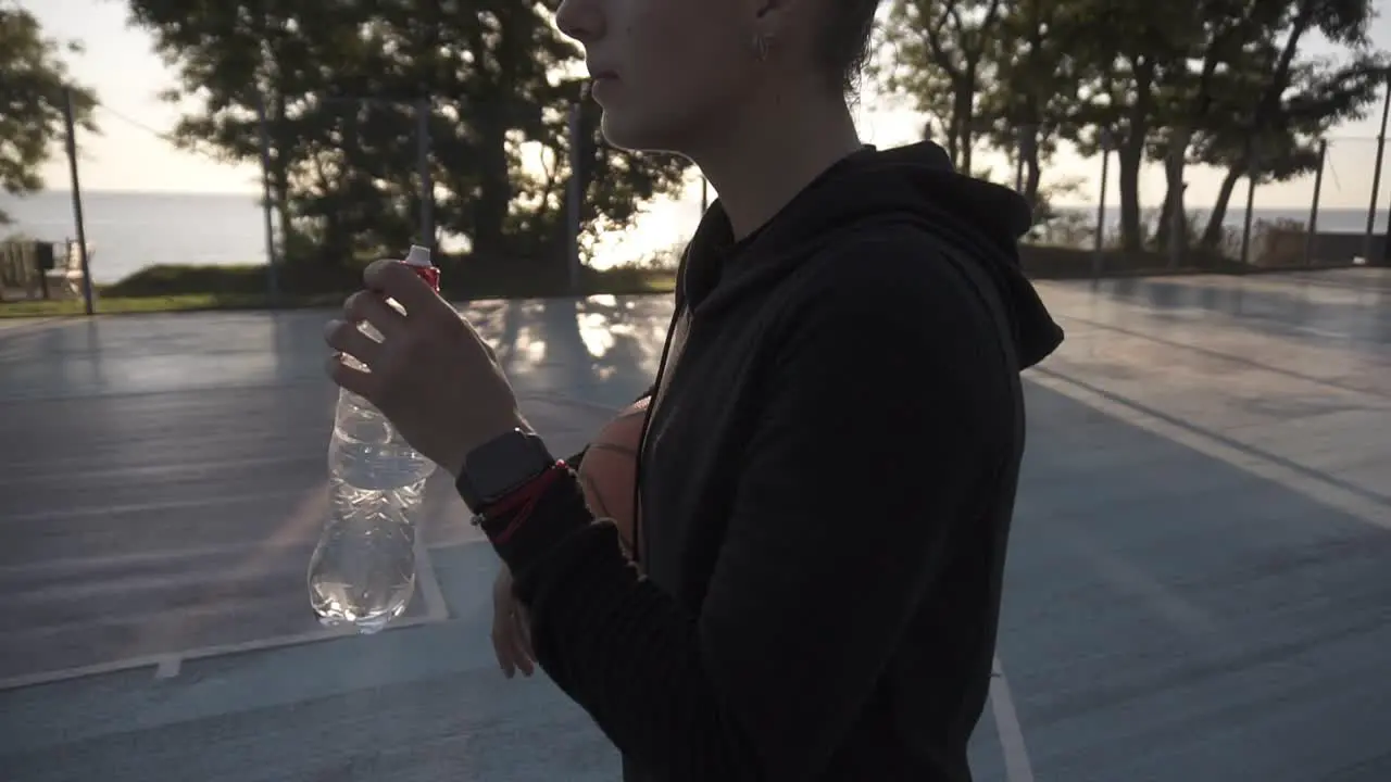 Down Up Footage Of A Young Sporty Girl Basketball Player Have A Rest After Training On The Local Outdoors Court Drinking A Water From A Plastic Bottle