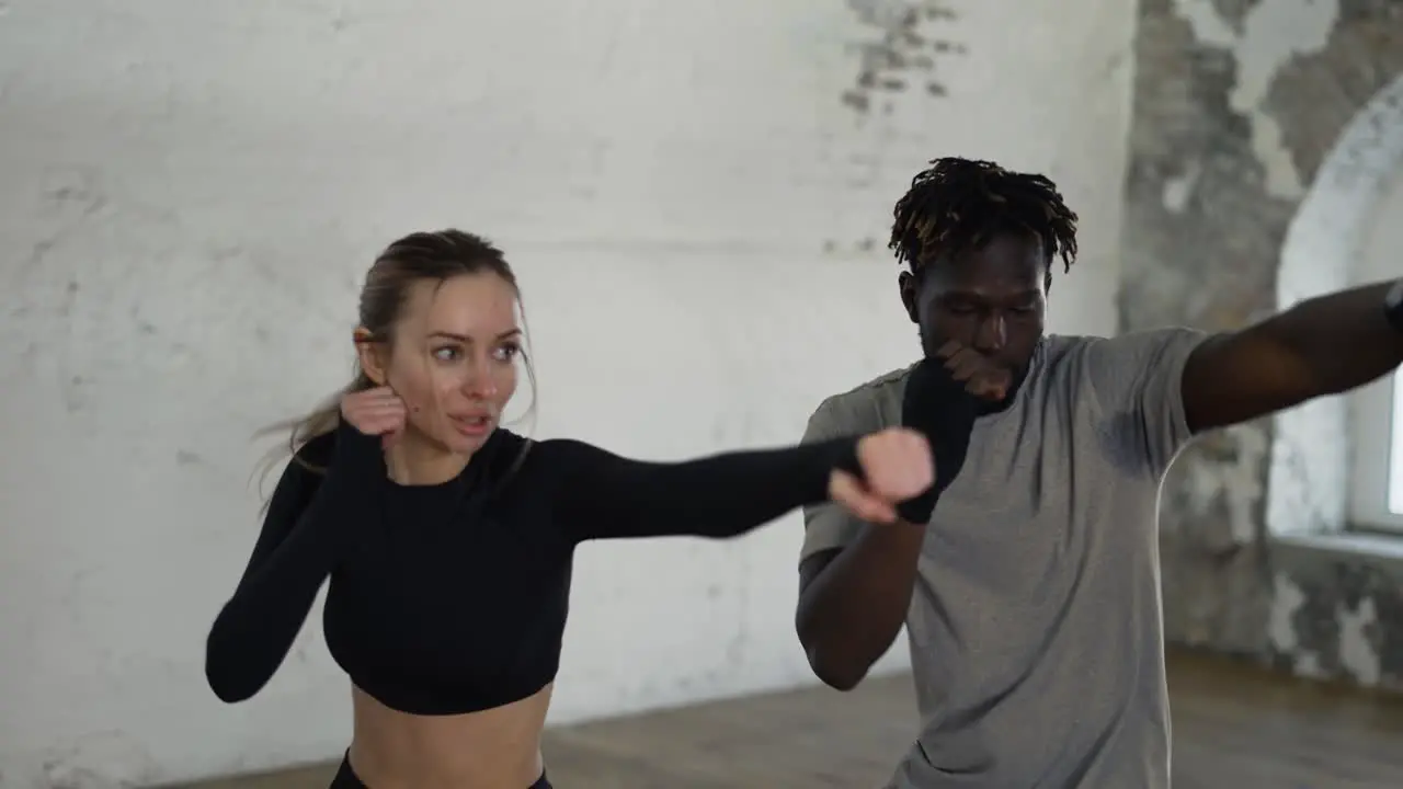 Trainer And His Female Student Conduct A Boxing Training Session Practicing Kicks