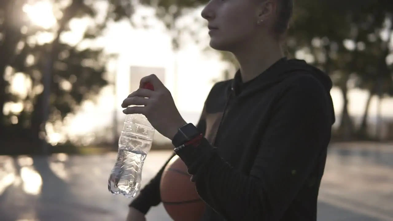 Down Up Footage Of A Young Sporty Girl Basketball Player Have A Rest After Training On The Local Outdoors Court Drinking A Water From A Plastic Bottle 1