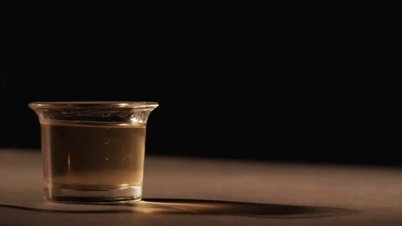 Video of lit alcohol in glass with yellow fire flames and copy space on black background