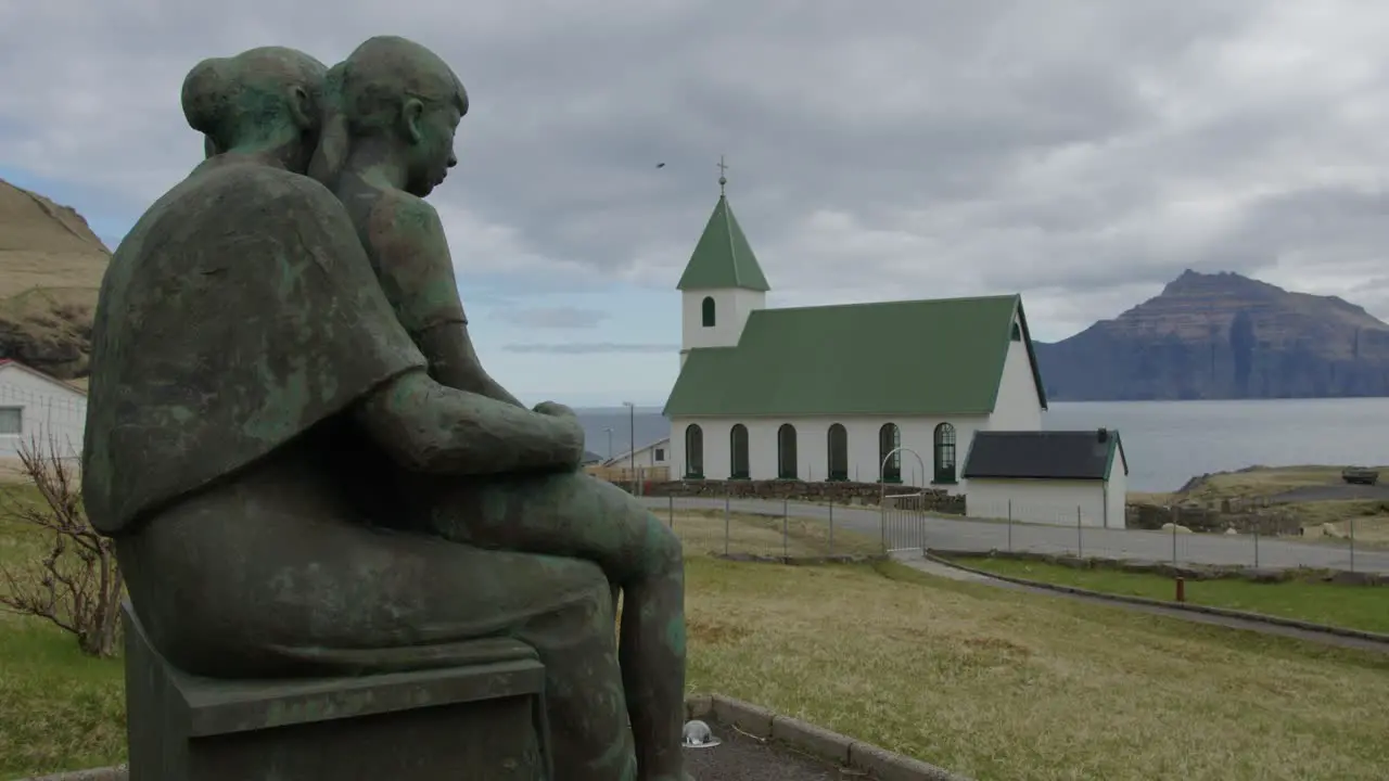 Wide Pan Right of a Memorial Statue and Church in Gjogv Faroe Islands