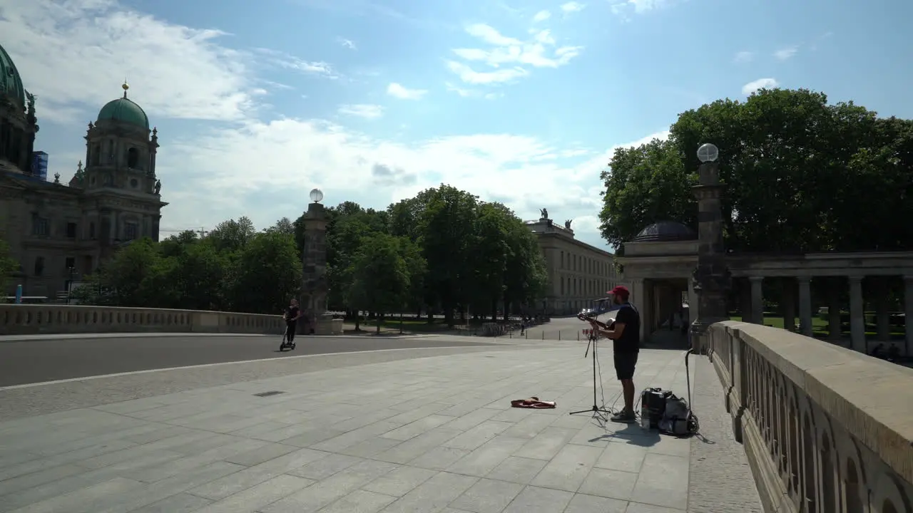 Street Performer Playing Guitar on Friedrichs Bridge With Berlin Cathedral in Background in Berlin Germany