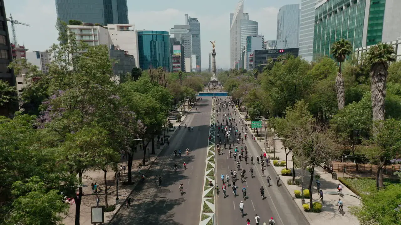 Aerial wide angle drone above cyclists at road near monument to independence