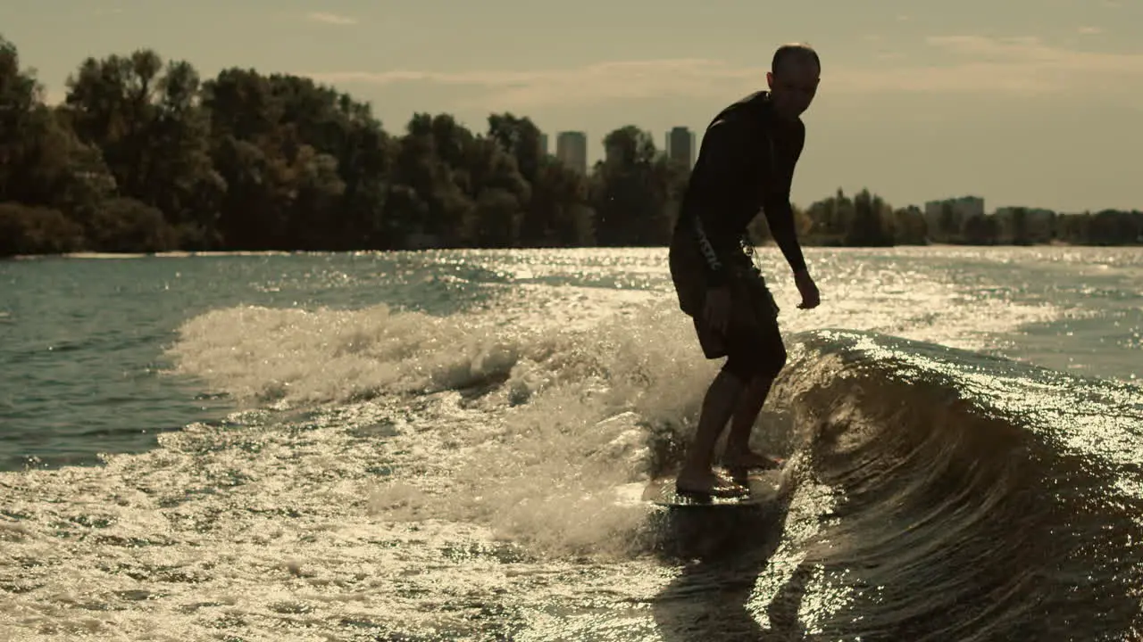 Man surfing on waves Sportive man surfing on wakeboard in slow motion