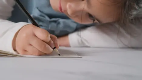 Studio Shot Of Young Girl At Table Writing In School Book 2