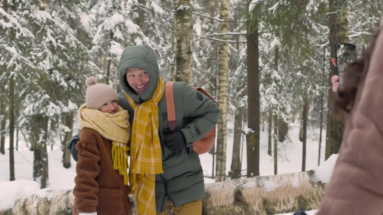 Rear View Of A Woman Taking A Photo Of Her Husband And Daughter In The Snowy Forest 1