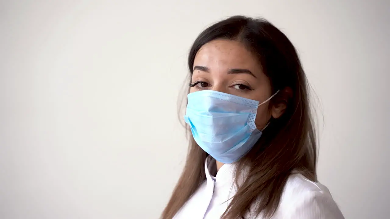 Portrait Of Female Doctor Putting On Medical Mask And Making The Ok Gesture