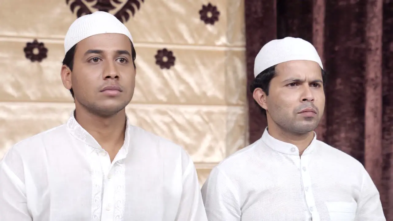 Two serious Indian Muslim men staring at something