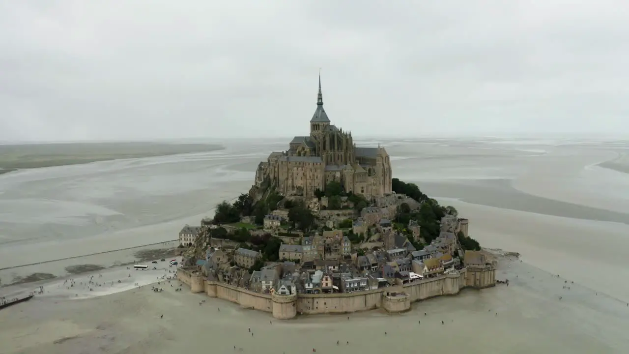 mont saint michel drone camera going towards the castle low rise there are many trees around the buildings