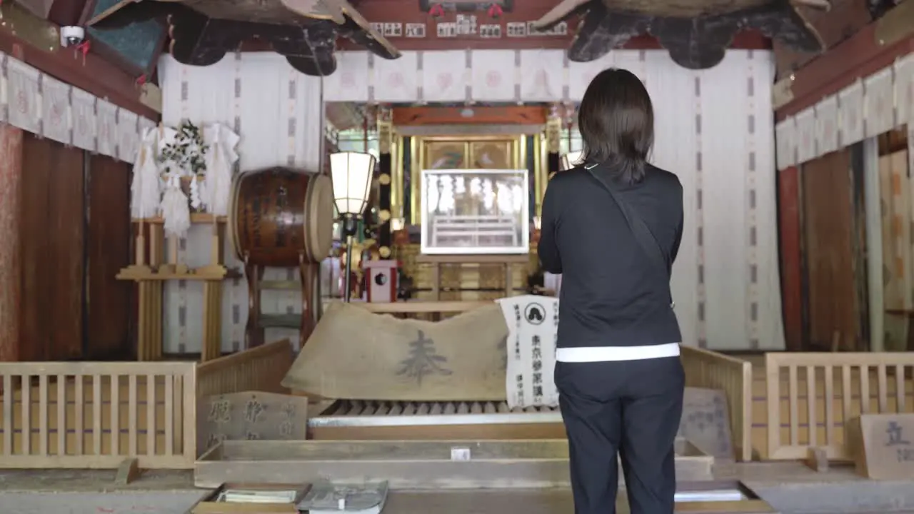 alone woman praying shinto temple tracking dolly in shot